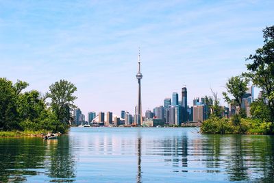 Cn tower and skyscrapers by lake ontario against sky