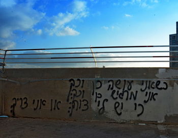 Graffiti on wall by building against sky