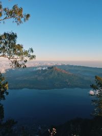 Scenic view of lake by mountains against clear blue sky