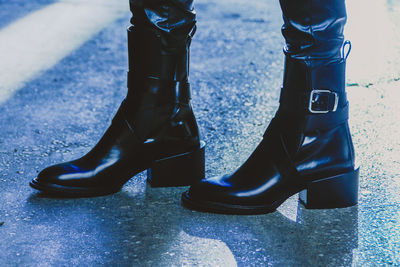 Low section of woman wearing boots while standing on road