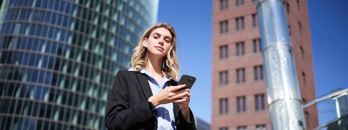 Portrait of young woman standing against building