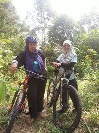 Portrait of young couple on bicycle in forest