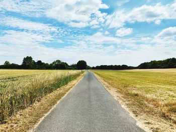 Road amidst field against sky