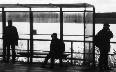 Rear view of silhouette people walking on railing