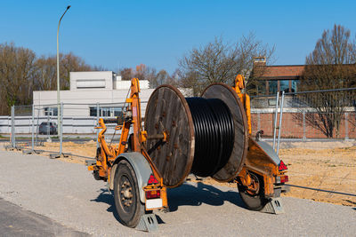 A wooden reel with an electric cable is mounted on a two-wheeled trailer. construction site. 