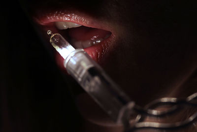 Cropped lips of woman by illuminated string light in darkroom