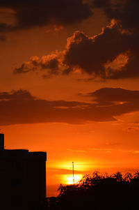 Silhouette building against orange cloudy sky