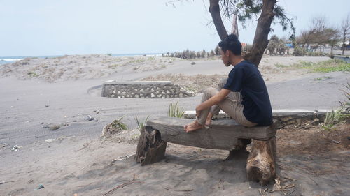 Side view of man sitting on beach