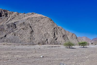 Scenic view of desert against clear blue sky