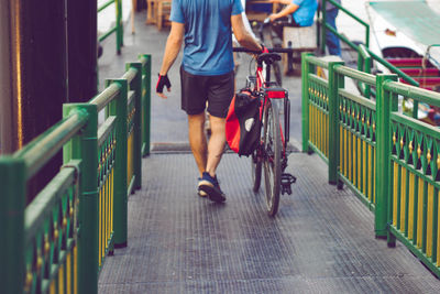 Low section of man with bicycle walking on footbridge