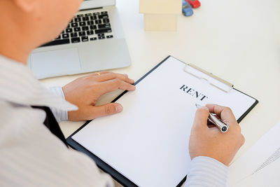 High angle view of real estate agent signing on rent papers at desk