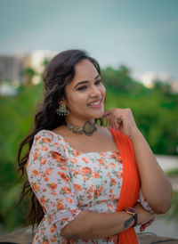 Portrait of young woman standing against trees