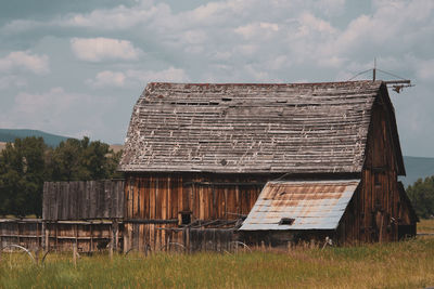 Old barn on field against sky