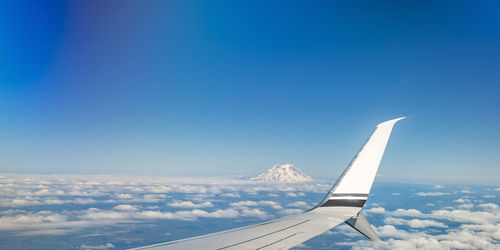 Airplane flying over clouds against blue sky