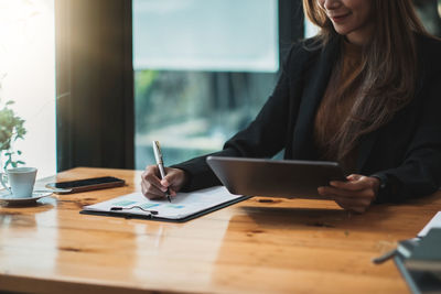 Midsection of woman using mobile phone while sitting on table