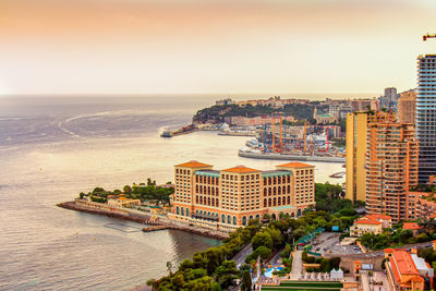 High angle view of townscape by sea against sky during sunset