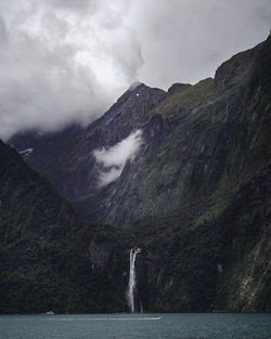 Scenic view of waterfalls through the mountains against a cloudy sky