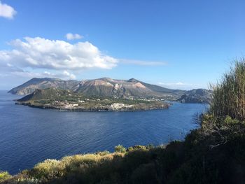 Scenic view of lake and mountains against blue sky