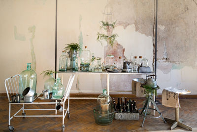 Empty chairs and table with glassware against wall at home