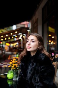 Portrait of woman looking at illuminated city at night