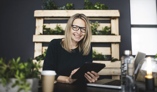 Portrait of smiling young woman using smart phone outdoors