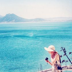 Side view of woman with camera against sea
