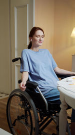 Young woman sitting on wheelchair at home