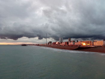 City at waterfront against cloudy sky