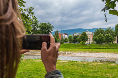 Man photographing through smart phone against sky