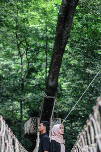 Man standing by tree trunk in forest