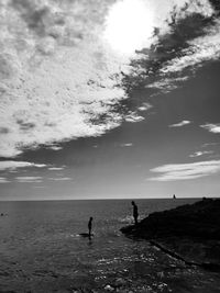 Silhouette people on beach against sky