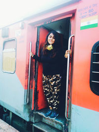 Portrait of young woman standing by train