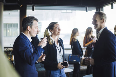 Male and female colleagues discussing while standing at workplace