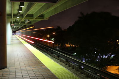 Illuminated railroad station against sky at night