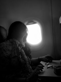 Rear view of woman sitting in airplane