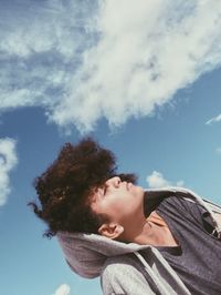 Low angle view of young woman with eyes closed against blue sky during sunny day