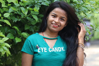 Close-up portrait of beautiful young woman standing against trees