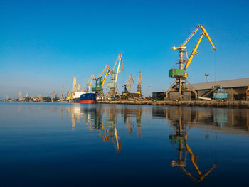Cranes at harbor against clear blue sky. panoramic view of port.