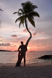 Full length of man standing at beach against sky during sunset