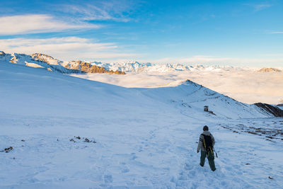 Rear view of woman hiking on snowcapped mountain