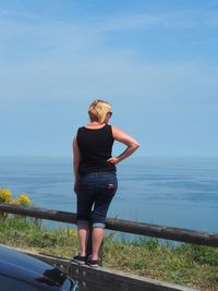 Rear view of woman standing at beach against clear sky