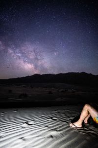 Low section of woman sitting on road against sky at night