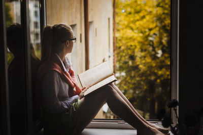 Side view of young woman reading book