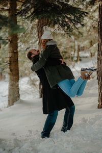 Couple embracing while standing on snow covered land