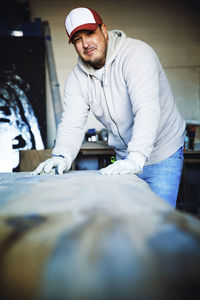 Portrait of smiling craftsman finishing wood at workshop