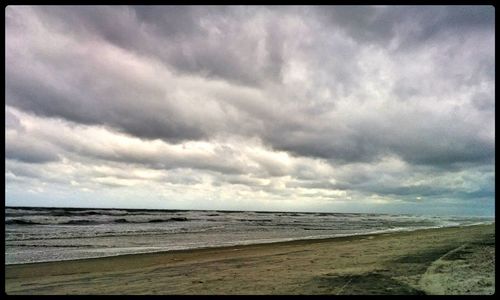Scenic view of beach against cloudy sky