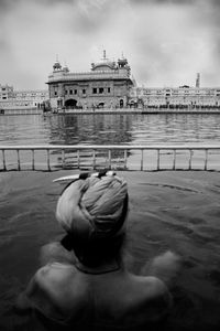Rear view of sikh man bathing at golden temple