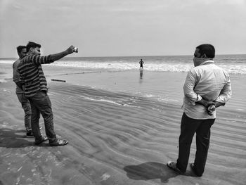 Rear view of men standing on beach