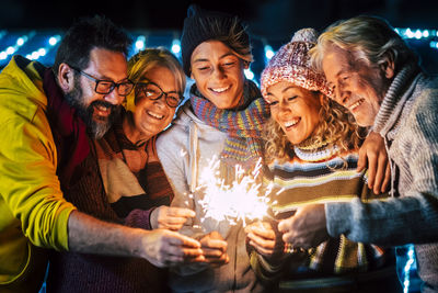 Cheerful family holding sparkler at night outdoors