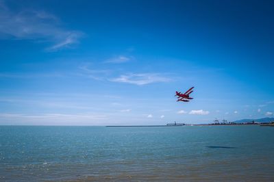 Airplane flying over sea against blue sky